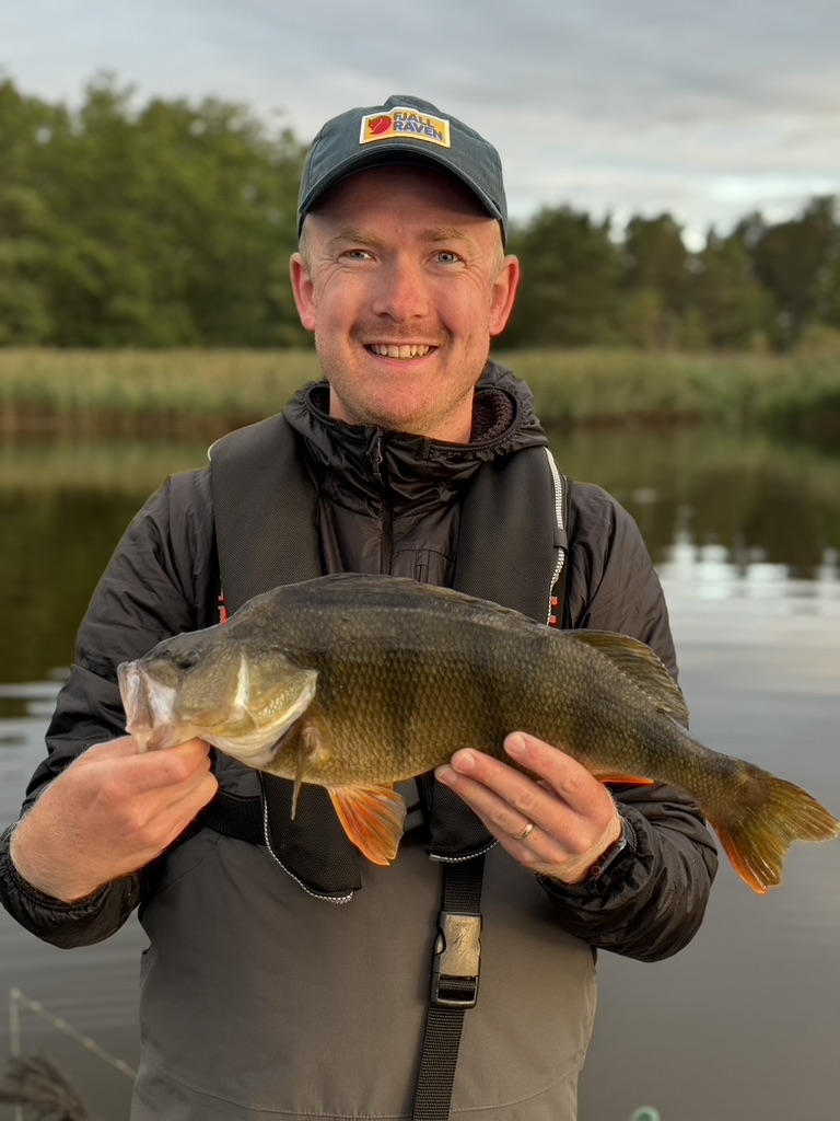 Oskar Källberg håller upp en abborre vid sjön